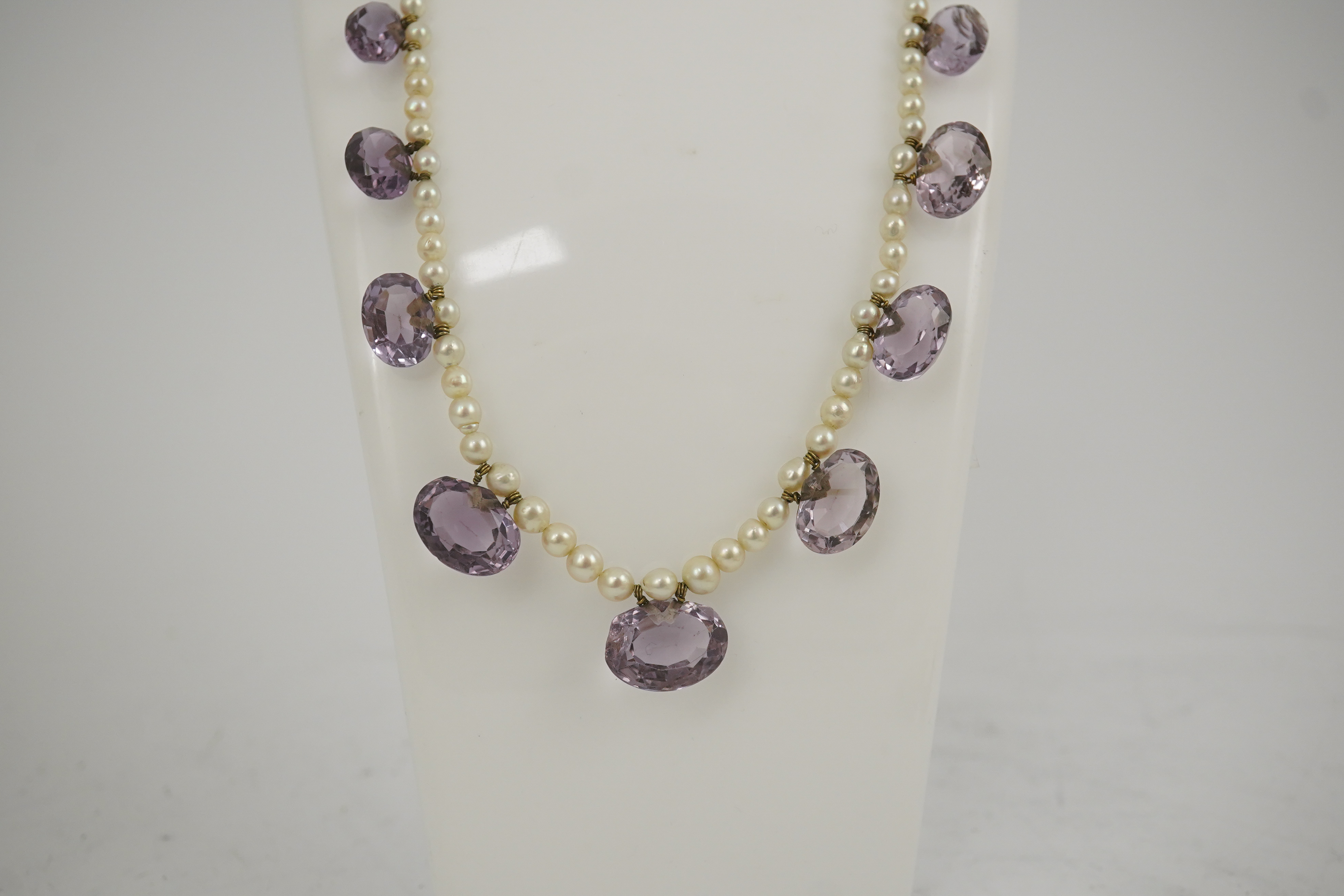 A 19th century pearl and graduated fifteen stone oval cut amethyst set drop necklace, with a gold barrel shaped clasp